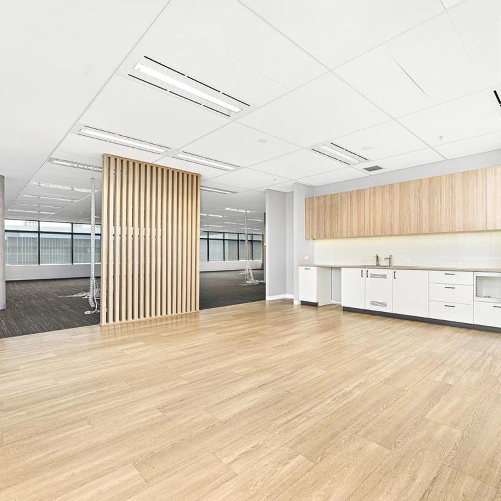 Bright, modern office space featuring wooden flooring, a stylish kitchen area, and a slatted partition separating work areas.