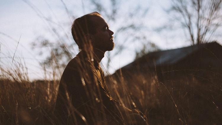 Man sitting in field of grass looking at sky