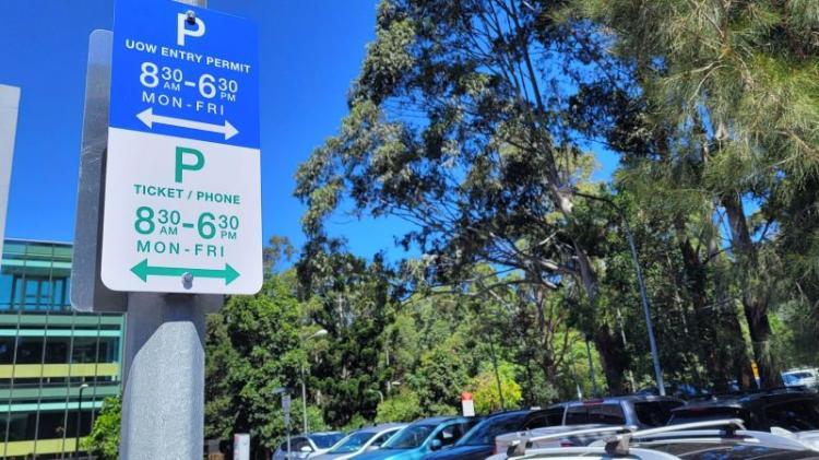 Parking sign in a UOW Wollongong campus car park with trees and cars in the background
