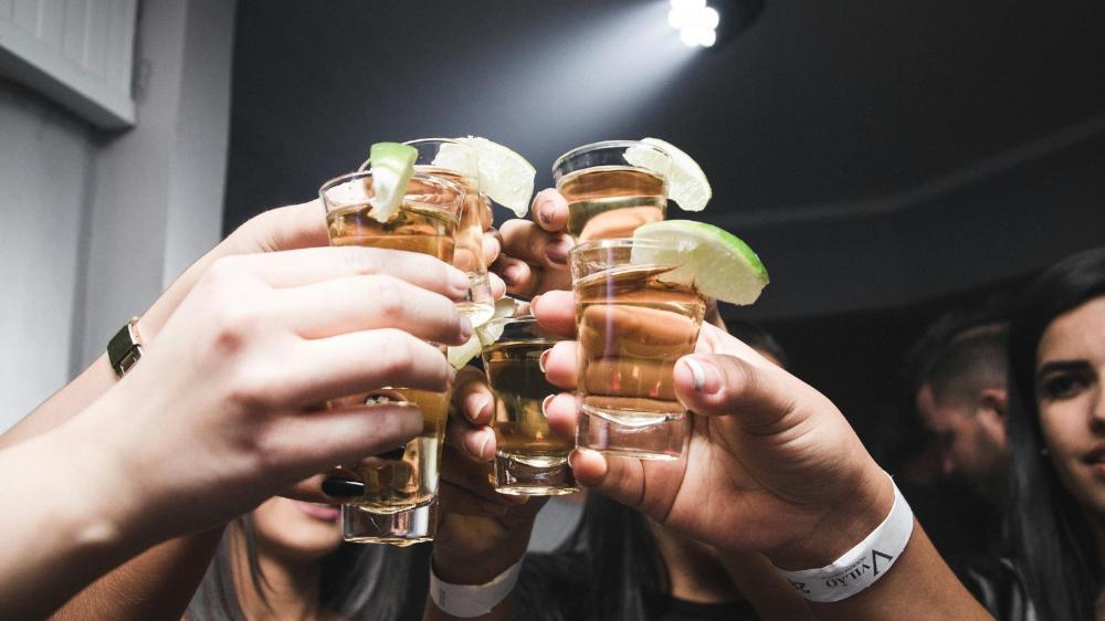 Hands holding shot glasses clinking glasses